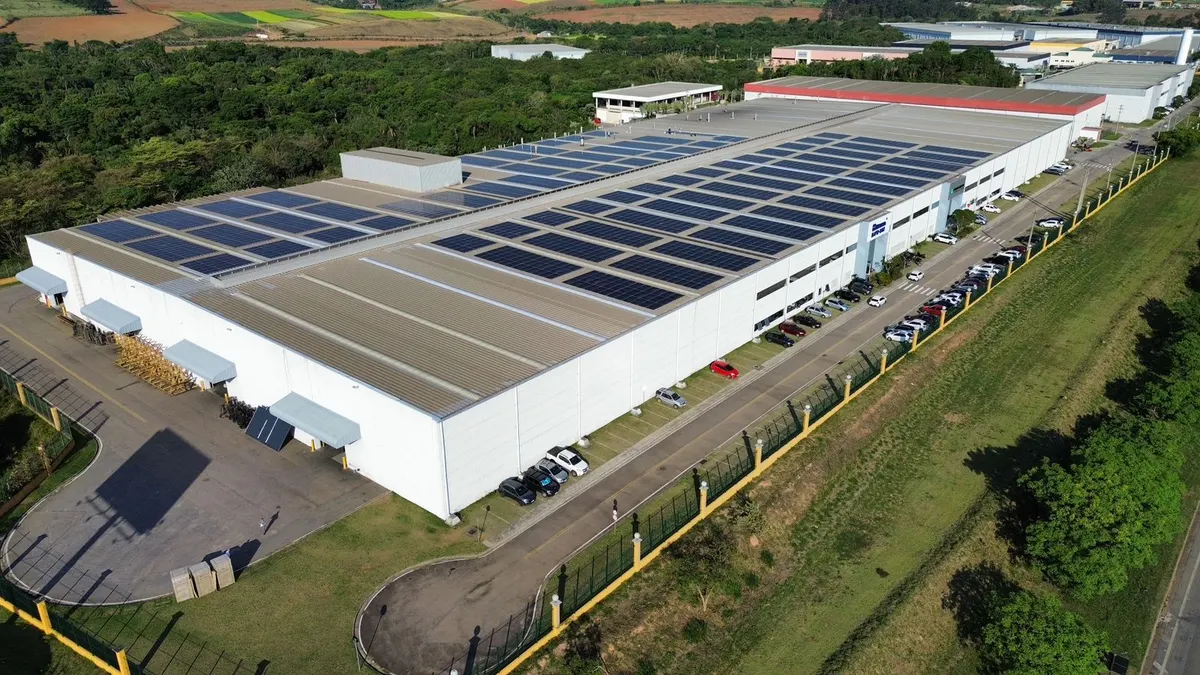 Galpão industrial com o telhado coberto de painéis solares, visto de drone