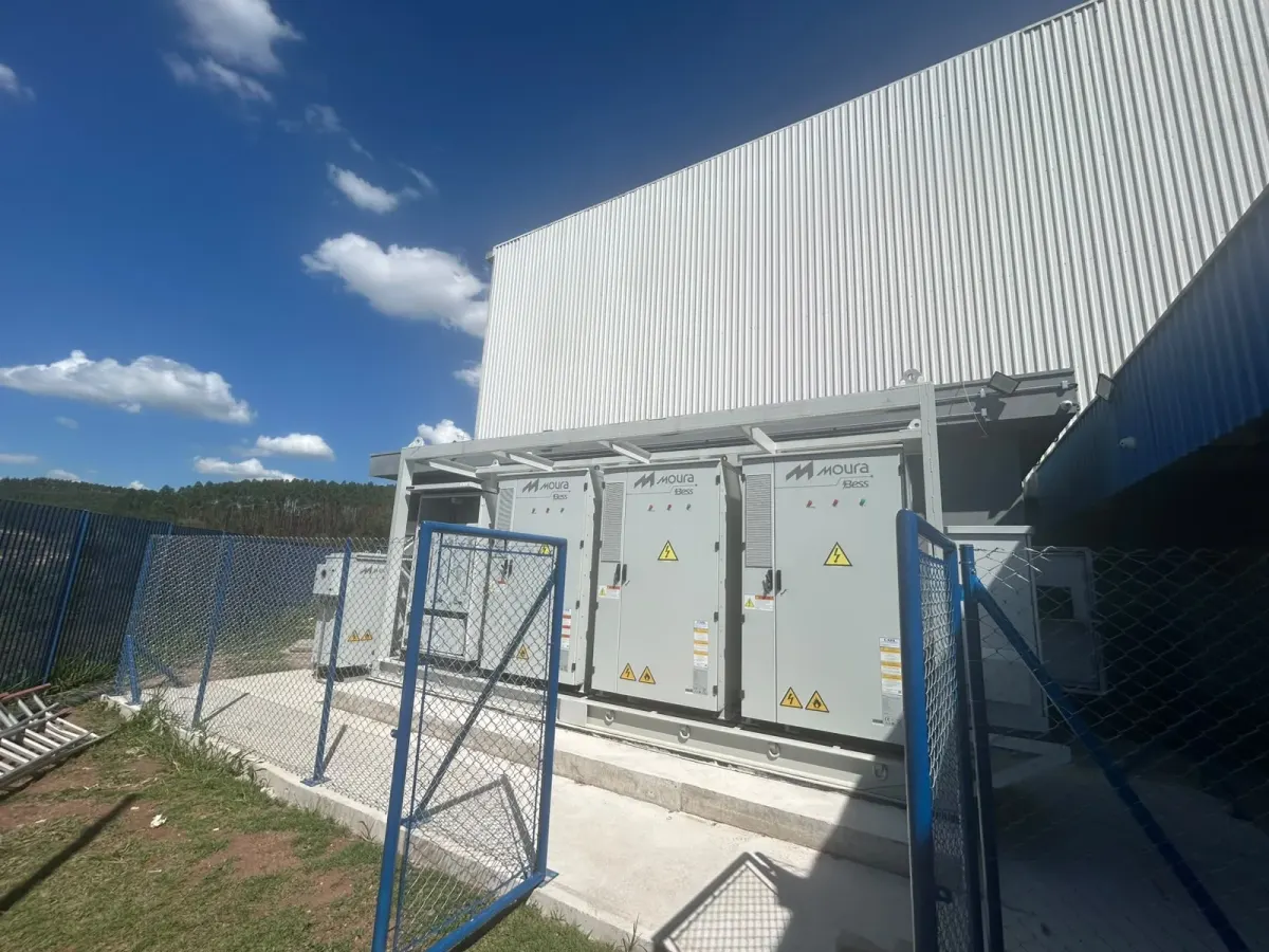 Gabinetes do BESS sobre a base de concreto, ao lado do galpão da Donaldson, atrás do alambrado azul