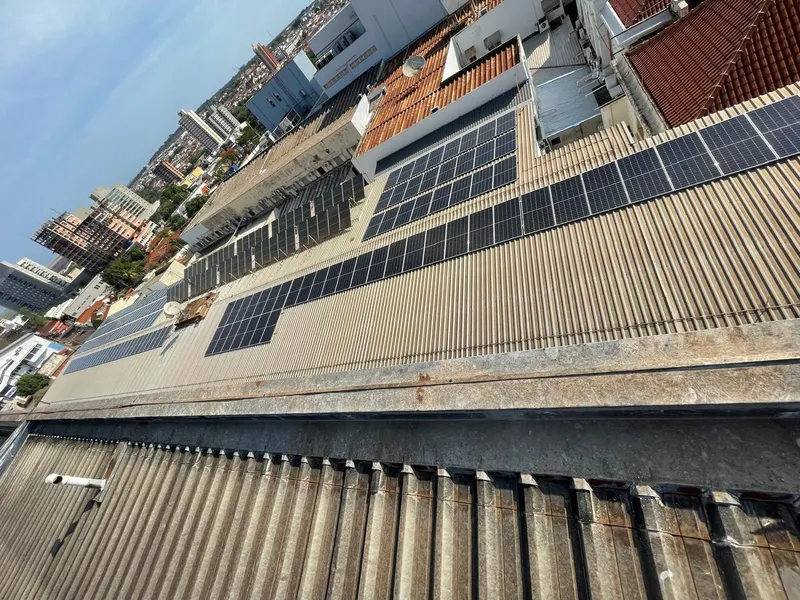 Telhado do Hospital Amaral Carvalho coberto de painéis solares, visto de cima, com os prédios de Jaú ao fundo