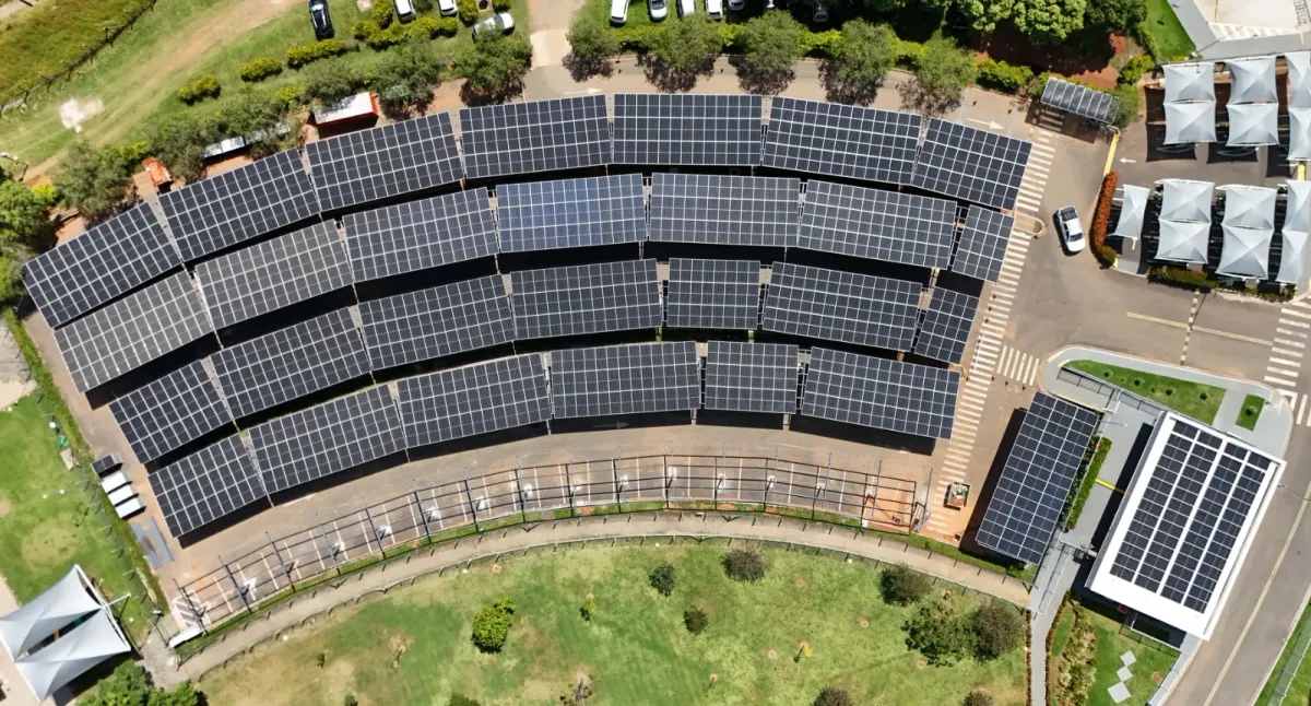Estacionamento visto de drone, com as fileiras em arco de carports cobertos de painéis solares